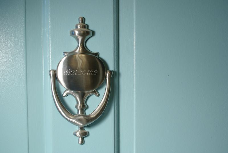 A door knocker engraved 'Welcome' on a painted front door