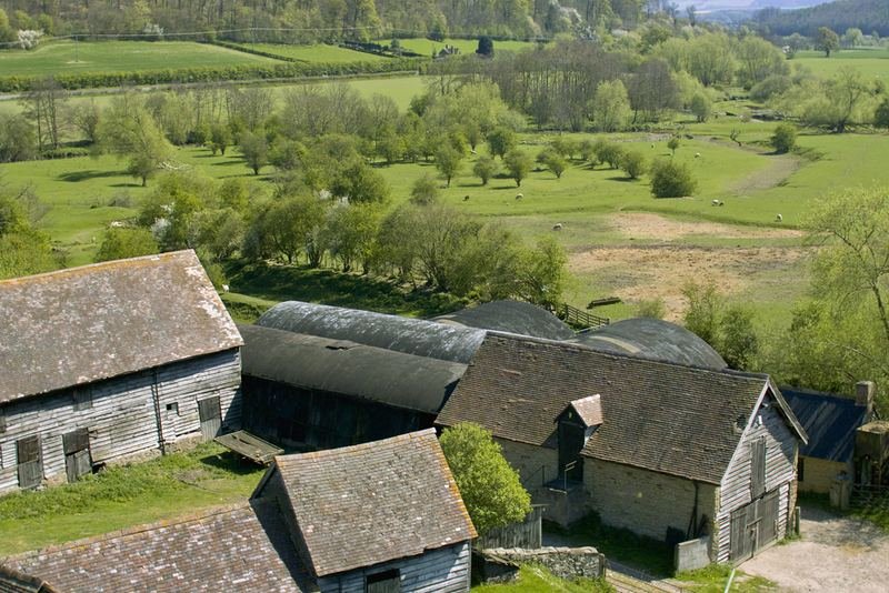 Old stone farm buildings above a valley of small fields