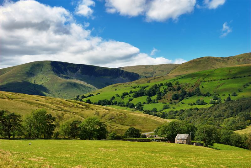 Green fells above a valley with a stone barn