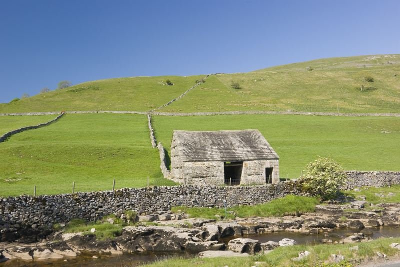 A stone field barn above a rocky beck
