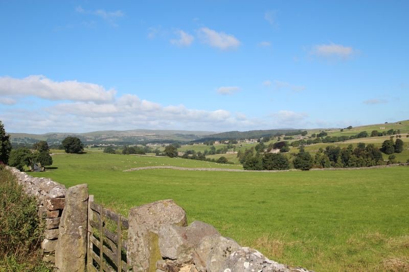 A field gate in a dry-stone wall, looking over a valley
