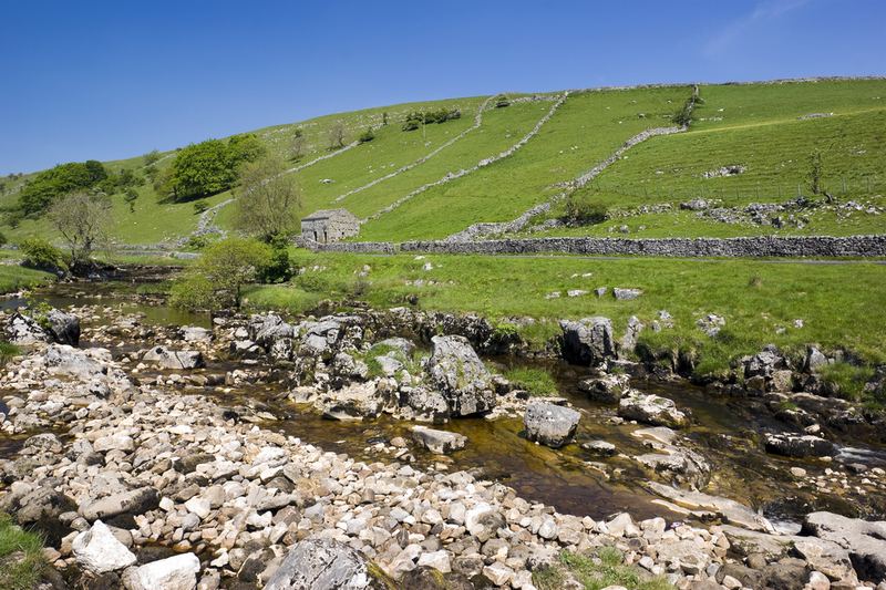 A rocky beck below walled hillside pastures