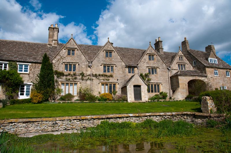 A long stone house with gables, across a lawn
