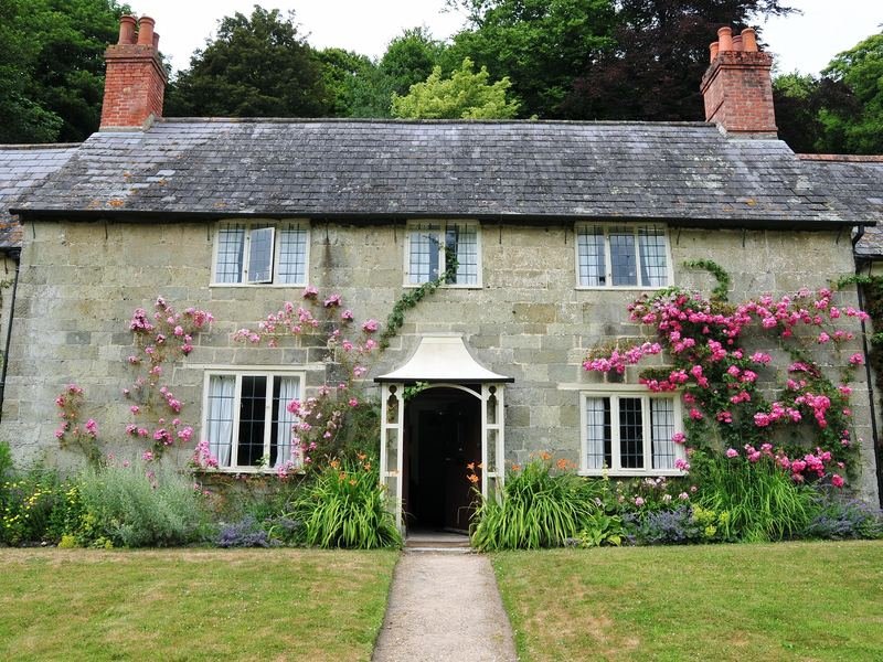 A stone cottage with roses round the door and a path through its front garden