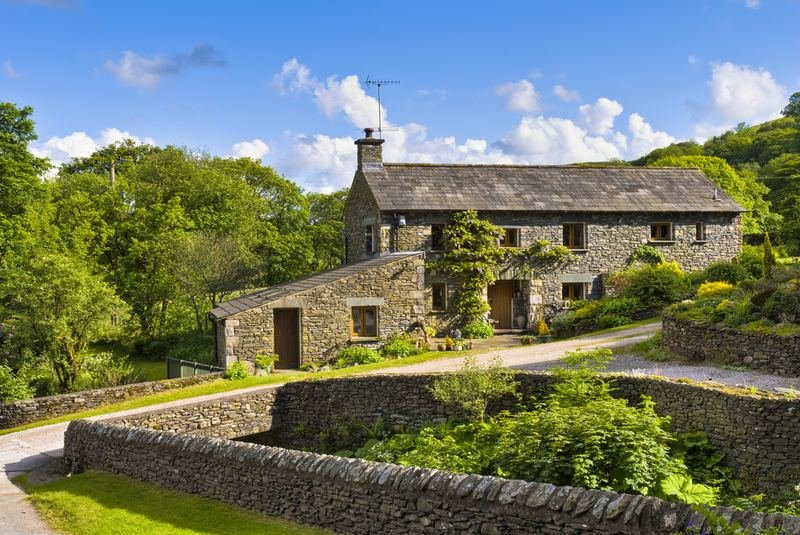 A stone farmhouse with dry-stone walls and a garden