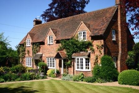 A brick cottage with climbing plants and a well-kept front lawn